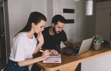 Evde proje üzerinde çalışırken günlük giysiler içinde bilgi ve dizüstü bilgisayar okuyan ve daktilo kullanan yoğun genç serbest çalışanların yüksek açısı