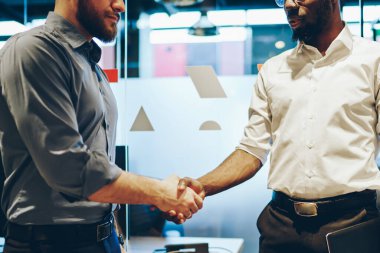 Sözleşme bittikten sonra gururlu CEO ve şirket yöneticisi arasındaki ortaklık görüşü. Resmi giyinmiş iki çok kültürlü girişimci ofiste birbirlerini selamlarken el sıkışıyorlar.