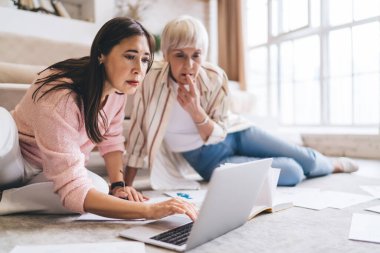 Başlangıç stratejisi üzerinde çalışırken gündelik giysiler içindeki yaşlanmış çeşitli meslektaşlar ekranlara bakarak yerde oturuyorlar.