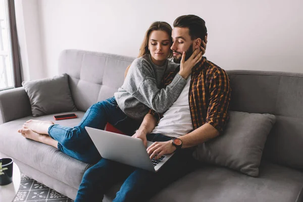 Girlfriend distracting boyfriend while he programming on remote on laptop computer, IT professional connecting to home internet for doing deadline job during time for bonding weekend with wife