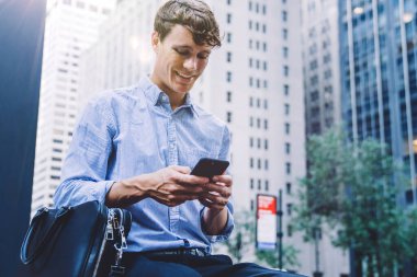 Genç işadamı, şehirdeki bankta otururken akıllı telefondan mesaj alıyor. LTE Internet 'te gezinen ve web sitesinde makale okuyan erkek çalışanlar. Milenyum halkı ve iletişim