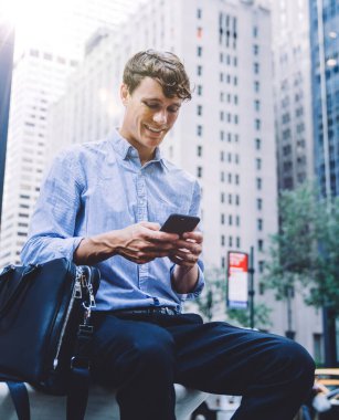 Genç işadamı, şehirdeki bankta otururken akıllı telefondan mesaj alıyor. LTE Internet 'te gezinen ve web sitesinde makale okuyan erkek çalışanlar. Milenyum halkı ve iletişim