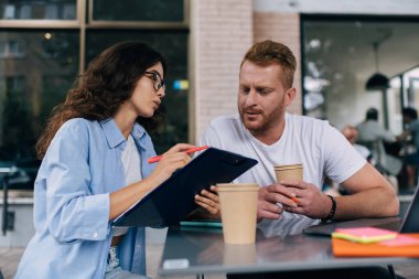 Kafkasyalı erkek ve kadın meslektaşlar, sokak kafeteryasında iş görüşmeleri sırasında evrak işlerini analiz ediyor ve tartışıyorlar. Birlikte iş birliği yaparken örgüt kurmayı planlayan zeki gazeteciler.