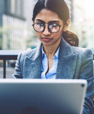 Şehir merkezinde açık havada otururken dokunmatik ped üzerinde çalışan, görme düzeltmesi için göz maskesi takan konsantre Hintli kadın girişimci şebekede haber okuyor. Milenyum işi.