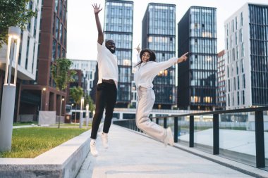 Modern şehir caddesinde birlikte eğlenirken kaldırımda gülümseyen ve zıplayan çok ırklı arkadaşlarla dolu bir vücut.