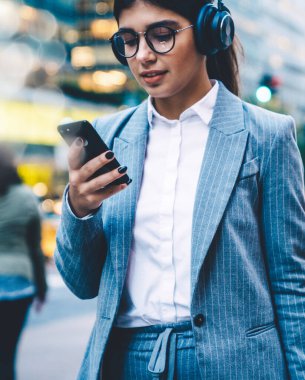 Kulaklıkla müzik listesinden keyif alan çekici genç bir iş kadını akıllı telefondaki LTE internetine göz atıyor. Cep telefonundan mesaj atan ve müzik dinleyen bir kadın. Sosyal ağlardaki ortam içeriği