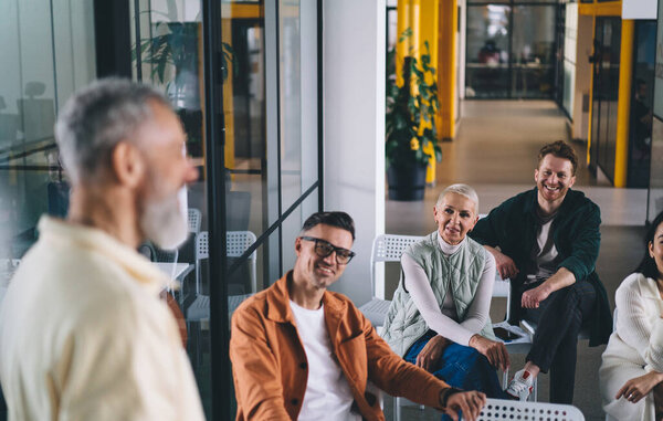 Group of multiethnic colleagues gathering at meeting with coworkers and sharing ideas during conversation about new strategy for startup project in modern workspace
