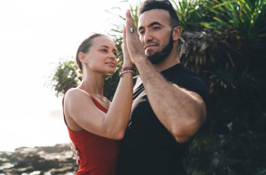 Güneşli bir günde parkta yemyeşil yeşilliklerin yanında Arjantin tangosu yaparken birbirine dokunan sevgi dolu genç çiftin yan görüntüsü.