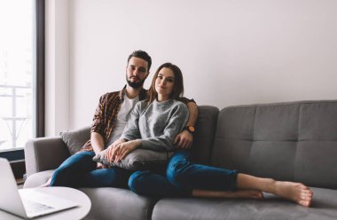 Romantik beyaz çift rahat koltukta dinleniyor ve aile bağları için boş zamanlarında kameraya bakıyor.