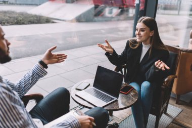 Tarlada gülen iş adamları şık kıyafetlerle masalarında alet ve cep telefonlarıyla oturup iş planı hakkında konuşuyorlar.