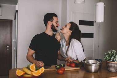 Mutlu erkek ve kadın eşler, kendi evlerinde birlikte yemek pişirmek için boş vakitlerin tadını çıkarıyorlar.