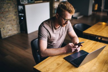 Mobil tebligat için cep telefonu uygulamasını kullanan beyaz erkek, laptop teknolojisiyle kablosuz internet sitesini akıllı telefon aygıtıyla tarayan milenyum adamı,