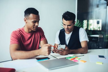 Farklı erkek arkadaşlar akıllı telefon uygulaması için uyarı mesajı okurken üniversite kampüsünde birlikte çalışma alanı olan birlikteliği öğreniyorlar, bin yıllık erkekler cep telefonuyla e-postaları kontrol ediyorlar