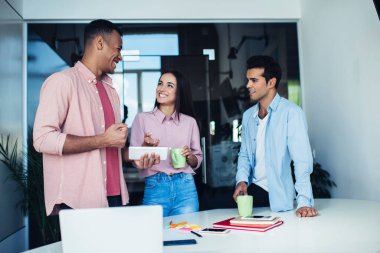 Sırıtkan entellektüel entelektüel iş arkadaşları dizüstü bilgisayarlarında kahve ve akıllı telefonlar taşıyorlar.