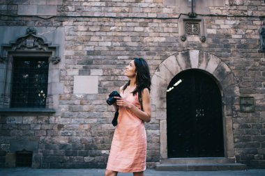 Ortaçağ taş binasının ön cephesini gören mutlu turistlerden. Gün ışığında sokakta durup kamerayla çekim yaparken.