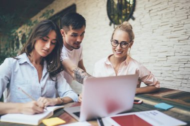 Bir grup mutlu iş adamı, terastaki modern kafede toplanırken dizüstü bilgisayarla birlikte çalışıyorlar.