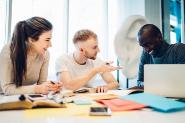 Çok ırklı çalışanlardan oluşan bir ekip, ofis binasında Joy 'la birlikte çalışırken notlar yazıp dizüstü bilgisayar kullanıyor.