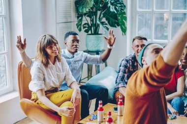 Siyahi şaşkın adam kollarını kaldırarak el kol hareketleriyle hareket ederken koltukta sakin bir kadınla otururken akıllı telefondan çeşitli arkadaşlarıyla çeşitli odalarda selfie çekiyordu.