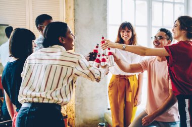Neşeli, güler yüzlü genç, çok ırklı insanlar gündelik giysiler içinde, aydınlık geniş çatı katında şişeleri tokuşturup, tıkırdatıyorlar.