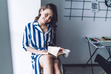 Çizgili, siyah saçlı, sevimli bir bayan. Evde kitap ve kahve fincanıyla iyi vakit geçiriyor ve kameraya bakıyordu. 