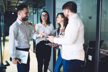 Çeşitli heyecanlı ofis çalışanları önemli belgeler taşıyor ve modern ofis koridorlarında işle ilgili konuları tartışıyorlar.