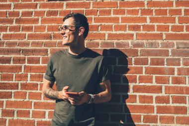 Görme düzeltmesi için optik gözlük takan erkek blog yazarı sosyal ağdaki profili güncellemeyi düşünürken reklam metni ve jenerasyon için promosyon arka planının yanında duruyor.