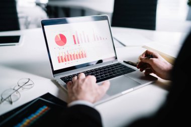 Ekin işadamı, ticaret şirketinin hafif ofisinde istatistiksel veriler üzerinde çalışırken gözlükleriyle masada oturuyor. 