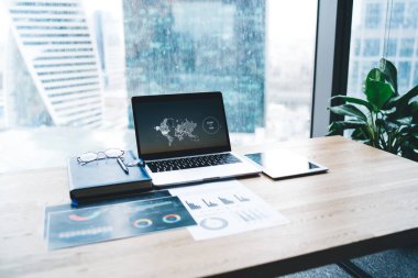 Gündüz vakti modern ofiste tabletin ve istatistik grafikli kağıtların yanında çizelge ve tabletle birlikte açılan dizüstü bilgisayar