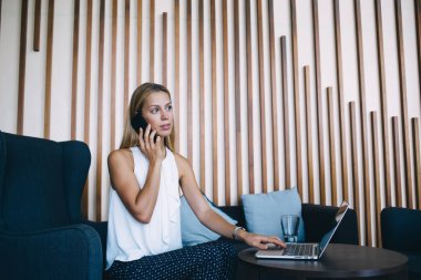 Genç girişimci akıllı telefon kullanarak iş hakkında konuşuyor. Dizüstü bilgisayar kullanıyor. Kendine güvenen, gururlu bir kadın CEO modern tasarımla cep telefonuyla konuşuyor.