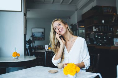 Kafkasyalı gülümseyen sarışın kadın cep telefonuyla konuşuyor. Kafeteryada rahat bir kafeteryada boş zamanlarının tadını çıkarıyor. Çekici genç hippi kız kafeteryada akıllı telefon konuşmaları yapıyor.