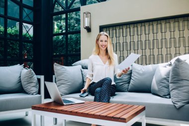 Kameraya bakan neşeli beyaz kadın portresi başarılı bir şirket kurma konusunda heyecanlı, boş kağıt tutan ve Jo için dizüstü bilgisayar kullanan kadın serbest yazar.