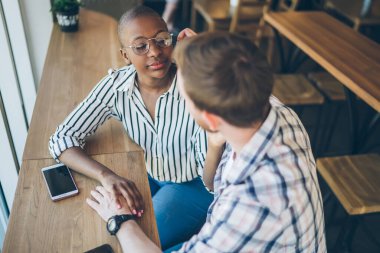 Yukarıdaki genç adam gözlüklerin çerçevesini düzeltirken sakin Afro-Amerikan otururken ve parlak kafede gözlerini kapatırken