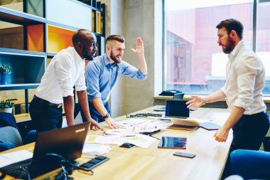 Resmi olarak gülümseyen yakışıklı erkek, modern ofis odasında iş arkadaşlarının beşlik çakmasıyla başarılı bir başlangıç yapıyor.