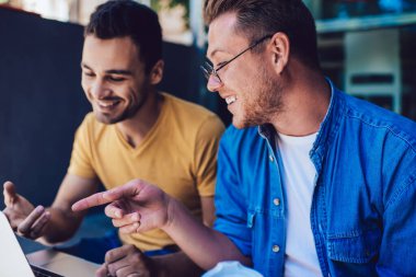 Zengin erkekler dizüstü bilgisayarı işaret eden profesyoneller projedeki işbirliğinden memnun olan internet sitesi, sosyal ağlarda gülen mutlu hipsterler birbirleriyle konuşuyorlar.