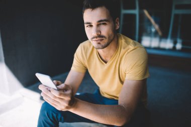 Düşünceli Kafkas erkek milenyumu. Gündelik kıyafetlerle boş zaman geçiriyor. Cihazlarla yazı yazıyor ve açık havada akıllı telefonla mesajlar yolluyor.