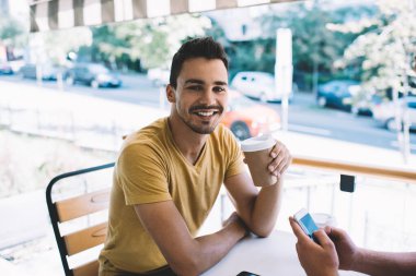 Kafe 'de arkadaşlarla buluşmaya giderken elinde tek kullanımlık kahve olan yakışıklı beyaz sakallı adamın yarım boy portresi. Kameraya bakan zengin, kendine güvenen bir adamın kırpılmış görüntüsü.