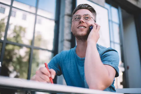 Θετικός Καυκάσιος Άνδρας Γυαλιά Που Μιλάει Στο Smartphone Κρατώντας Σημειώσεις — Φωτογραφία Αρχείου