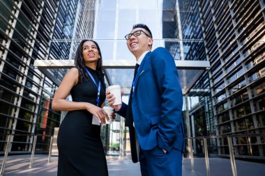 Mutlu iş kadınlarından, bir fincan taze içecek içip cebi para dolu Asyalı bir erkekle sohbet ederek iş yerinde ara verip başka yöne bakıyor.