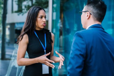 Siyah elbiseli, kendine güvenen İspanyol kadın takım elbiseli adamla iletişim kuruyor ve modern şehrin projesinin stratejisini tartışıyorlar.