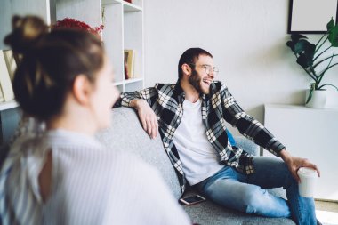 Kanepede oturan erkek, gülümseme ve günlük kıyafetlerle kahve ve şık modern odada oturan bayan.