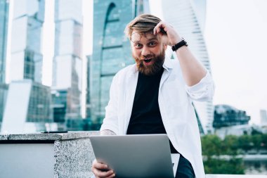 İçerik metinleri oluşturan heyecanlı erkek blog yazarının portresi dizüstü bilgisayarla alınan analitik smm istatistiklerine şaşırdı, netbook ile kameraya bakan Kafkasyalı serbest yazar şaşırdı