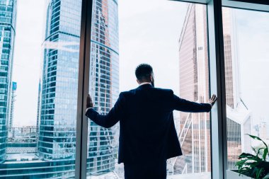 Ofisteki pencerelerden modern binalara bakarken ve dikilirken kendine güveni tam bir esnafın iş elbisesi planlama projesinin arka plan görüntüsü