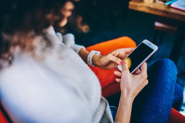Bacak bacak üstüne atmış giyinmiş, cep telefonu kullanan sosyal medyada sohbet eden, kafede dinlenen çiftçi bir kadın. 