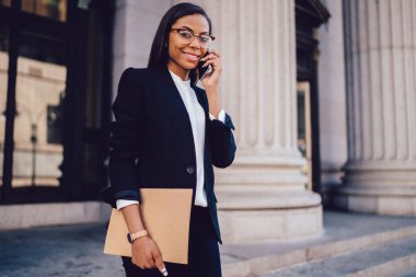 Afrika Amerika 'nın düşük açısı. New York caddesinde gülümseyen ve kameraya bakan, resmi giyinmiş, meşgul kadın girişimci. 