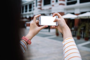 Kentin caddesindeki modern binalara karşı ekranda beyaz boşluklu akıllı telefonları tutan tanınmayan bir kadın.