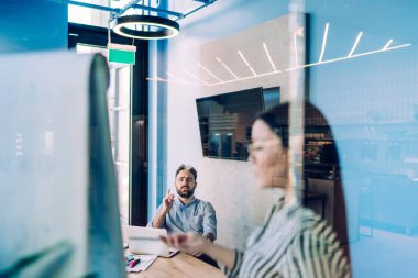 Düşünceli erkek dizüstü bilgisayarla masada oturuyor ve şirket ofisinde seminer verirken dikkatle meslektaşını dinliyor.