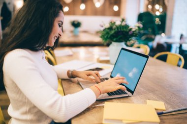 Sosyal ağların paylaşımı için içerik yayınını yazan milenyum blogcusu, 4G bağlantısı olan dizüstü bilgisayarda kablosuz tarama sırasında web bilgilerini arayan mutlu beyaz kadın