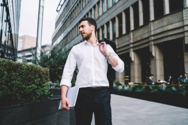Genç, işten sonra elinde dizüstü bilgisayarla sokakta yürüyen, omuzlarında ceket olan ciddi bir erkek müdürün dikkatini dağıttı.