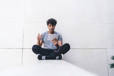 Günlük giysiler içinde şoke olmuş bir adam şehir ortamında oturmuş ve hesap bakiyesiyle ilgili bilgileri okuyordu. Elektronik kulaklıklı bir adam müzik uygulaması kuruyordu.