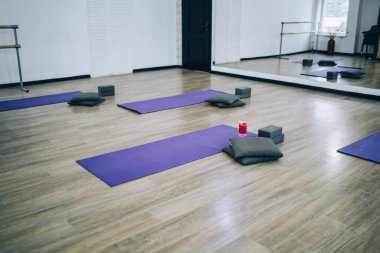 Ayna duvarları, mor paspası, yoga için yastıkları ve pürüzsüz zeminde egzersizleri olan rahat bir spor salonu. 